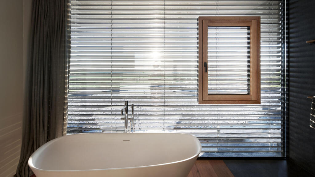 Innenansicht eines Badezimmers mit Blick auf das schwebende Fenster mit Raffstores – Böhler Fenster